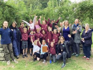 group of children and adults celebrating in front of trees